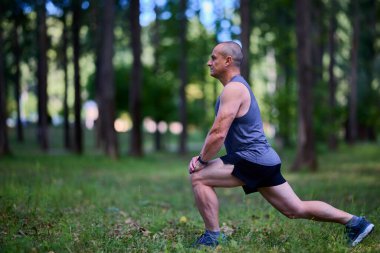 Parktaki erkek sporcu, koşudan önce ısınıyor ve ısınıyor..