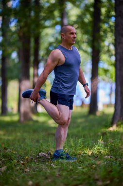 Parktaki erkek sporcu, koşudan önce ısınıyor ve ısınıyor..
