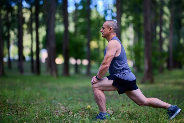 Parktaki erkek sporcu, koşudan önce ısınıyor ve ısınıyor..