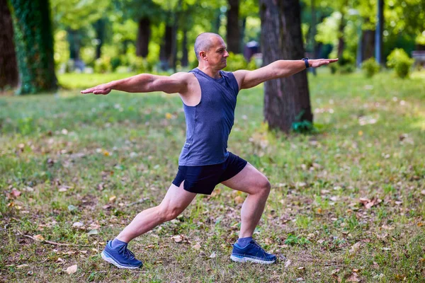 Parktaki erkek sporcu, koşudan önce ısınıyor ve ısınıyor..