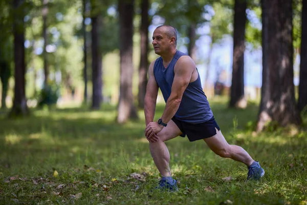 Parktaki erkek sporcu, koşudan önce ısınıyor ve ısınıyor..