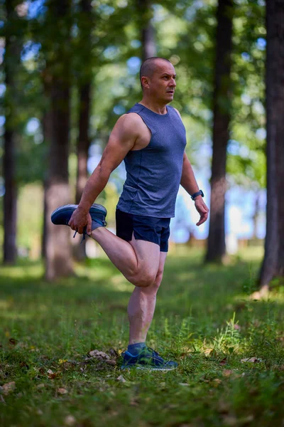 Parktaki erkek sporcu, koşudan önce ısınıyor ve ısınıyor..