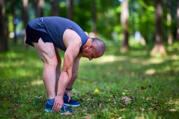 Parktaki erkek sporcu, koşudan önce ısınıyor ve ısınıyor..