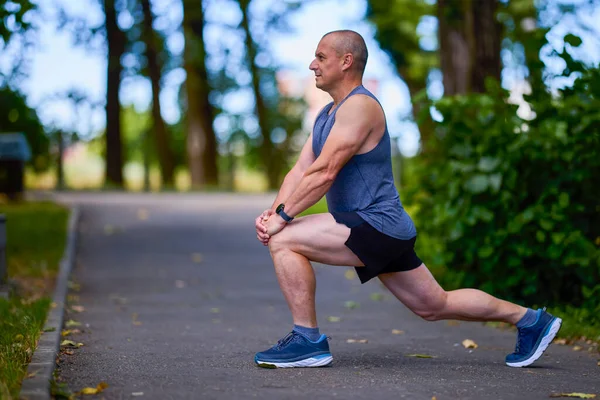 Parktaki erkek sporcu, koşudan önce ısınıyor ve ısınıyor..