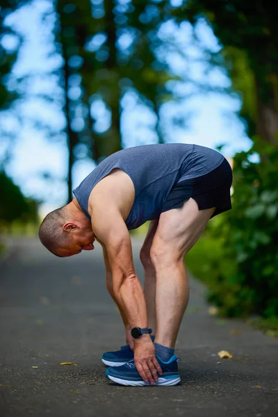 Parktaki erkek sporcu, koşudan önce ısınıyor ve ısınıyor..