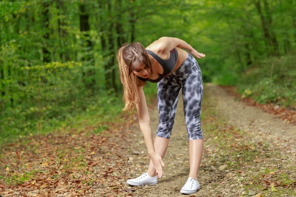 Hermosa joven haciendo ejercicio de estiramiento en el bosque de carretera — Foto de Stock