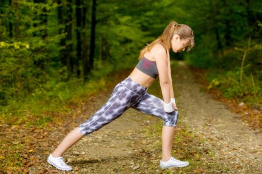 bir ormanda yol germe egzersiz yaparak güzel bir genç kadın