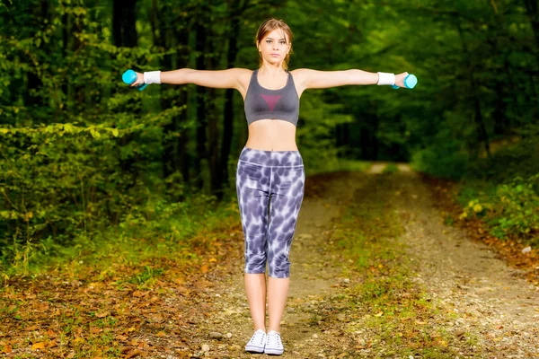 Beautiful young woman doing stretching exercise on road forest — Stock Photo, Image