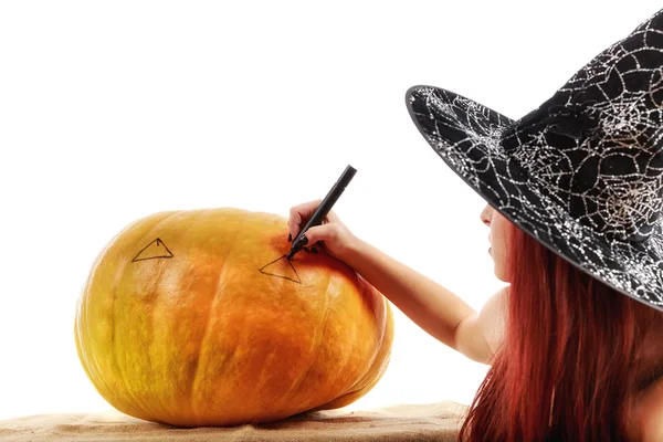 Portrait of a witch with red hair that draws on a pumpkin — Stock Photo, Image