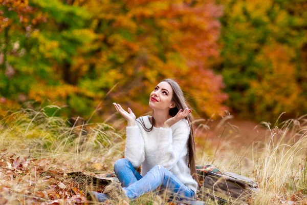 Ευτυχισμένη γυναίκα κάθεται στο έδαφος με τα χέρια ανοιχτά — Φωτογραφία Αρχείου