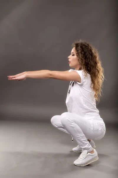 Hermosa mujer con pelo rizado haciendo ejercicio aislado en gris —  Fotos de Stock