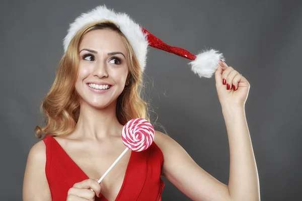 幸福的微笑女孩穿着圣诞老人的衣服为基督持有一颗糖果 — 图库照片