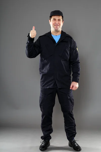 A security guard with a thumb up sign, isolated on grey — Stock Photo, Image