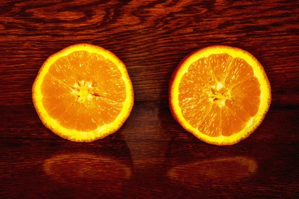 Orange cut in half on wooden table — Stock Photo, Image