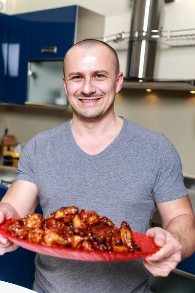 Homme présentant un plateau d'ailes de poulet caramélisé — Photo