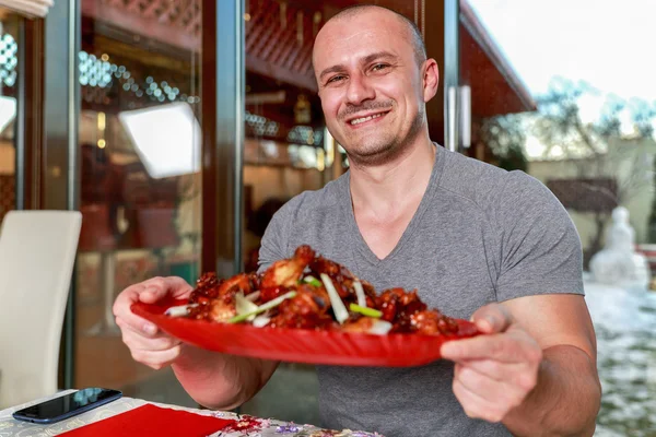 Homme présentant un plateau d'ailes de poulet caramélisé — Photo