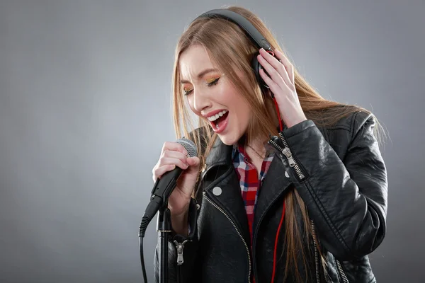 Vrouw met hoofdtelefoon en microfoon zingen — Stockfoto