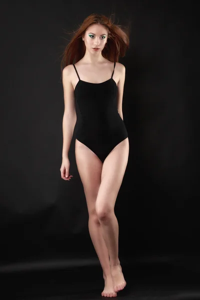 Beautiful woman in a black bodysuit posing on a black background — Stock Photo, Image