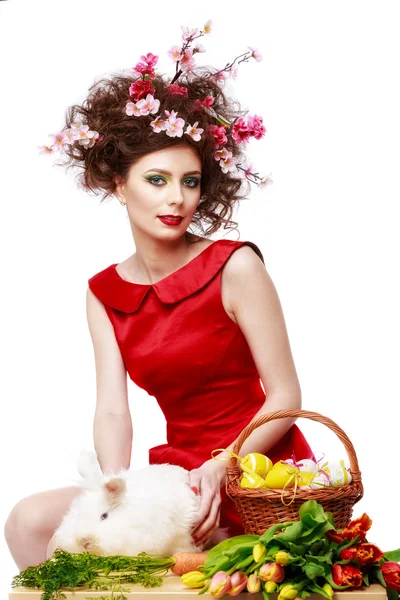 Mujer con un conejo, huevos y flores primavera Pascua concepto — Foto de Stock