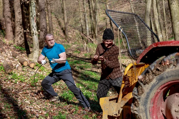 Old man and a strong man working with a tractor — Stock Photo, Image