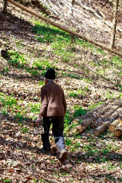 Vieil homme avec une tronçonneuse dans la forêt — Photo