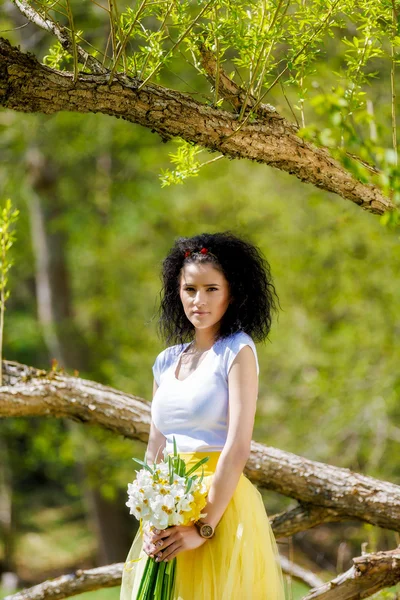 Piękna młoda kobieta z bukietem żonkile w przyrodzie — Zdjęcie stockowe