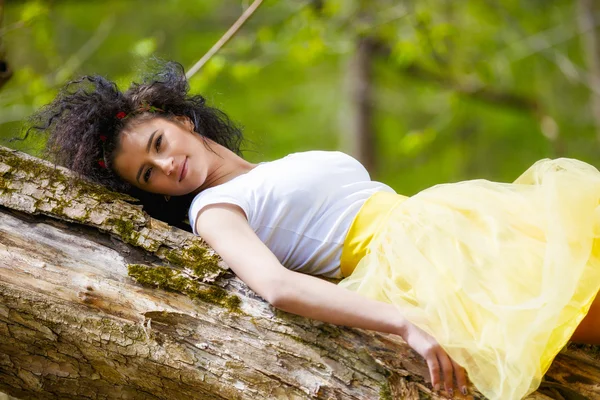 Beautiful young woman lies on a tree — Stock Photo, Image