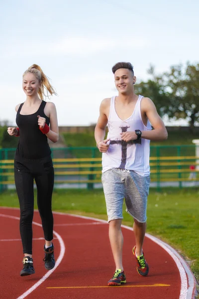 Un atractivo hombre y mujer corriendo en la pista — Foto de Stock