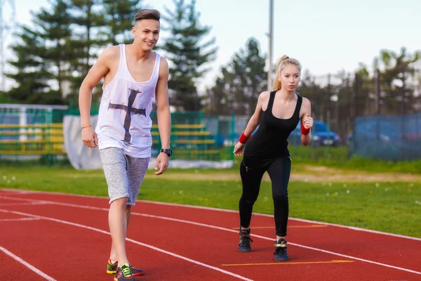 Un atractivo hombre y mujer corriendo en la pista — Foto de Stock