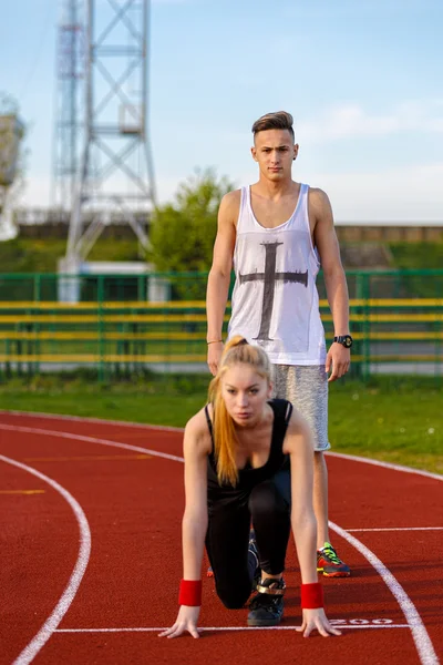 Pareja deportiva joven en posición inicial preparada para competir y — Foto de Stock