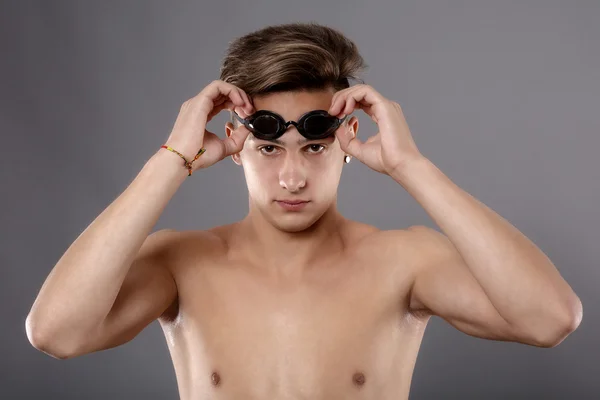 Porträt eines jungen Mannes mit Schwimmbrille auf grauem Hintergrund — Stockfoto