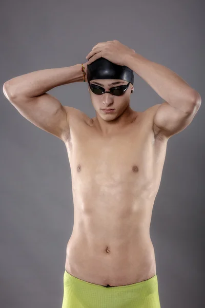 Porträt eines jungen Mannes mit Schwimmbrille auf grauem Hintergrund — Stockfoto