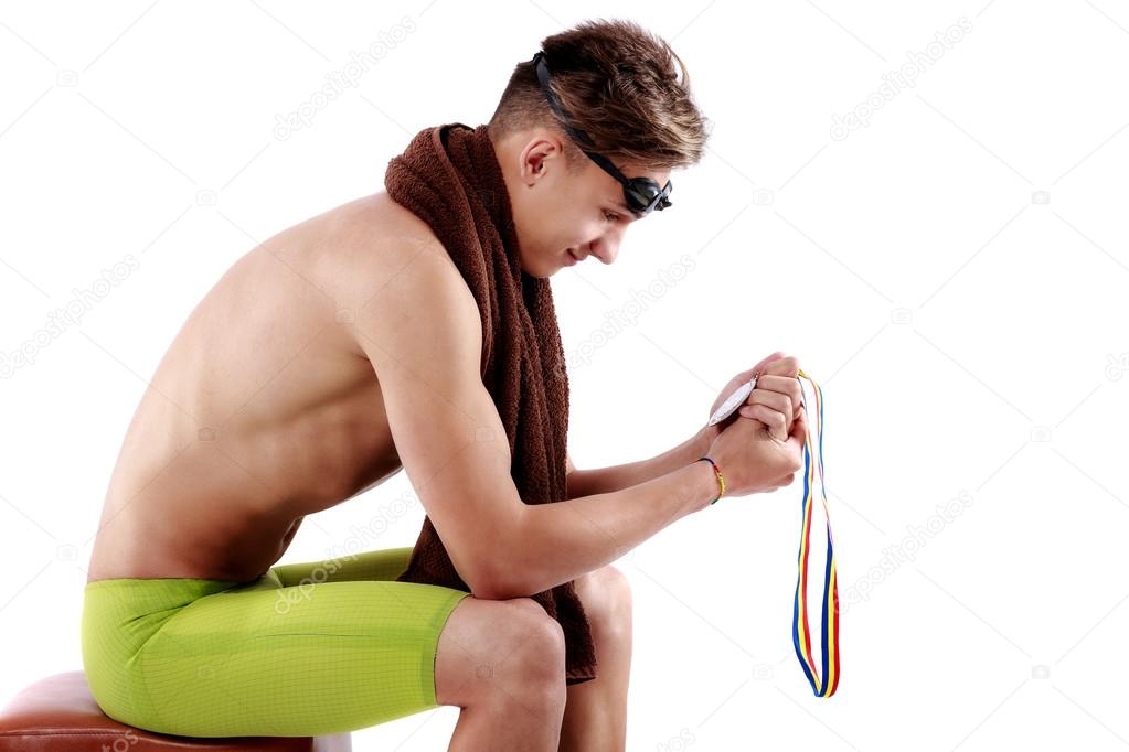 swimmer sits and looks at medal