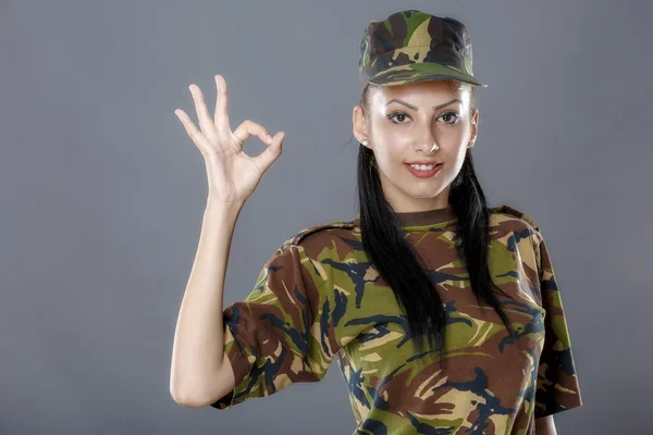 Female soldier in camouflage uniform looks ok sign — Stock Photo, Image