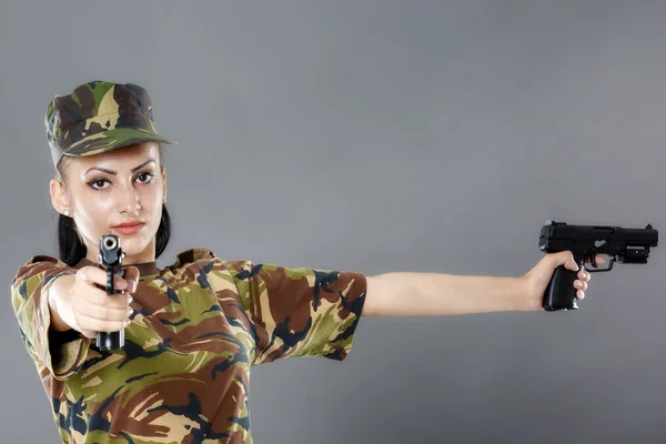 Kvinnlig soldat i kamouflage uniform med vapen isolerad på grå bakgrund — Stockfoto