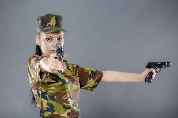 Soldado femenino en uniforme de camuflaje con arma aislada sobre fondo gris — Foto de Stock