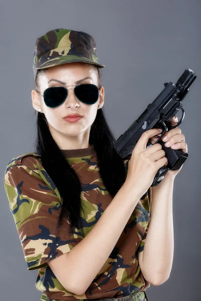 Kvinnlig soldat i kamouflage uniform med vapen isolerad på grå bakgrund — Stockfoto
