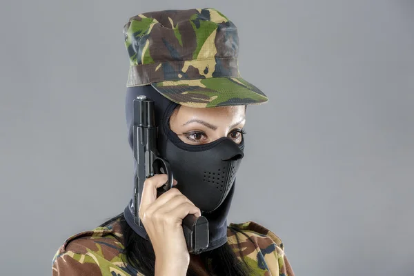 Kobiece żołnierz w kamuflażu jednolite z bronią na białym tle na szarym tle — Zdjęcie stockowe