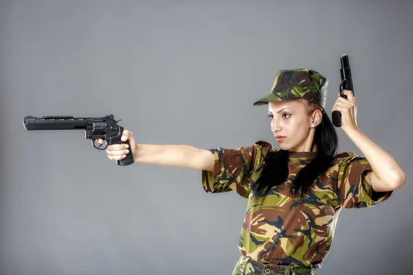 Kvinnlig soldat i kamouflage uniform med vapen isolerad på grå bakgrund — Stockfoto