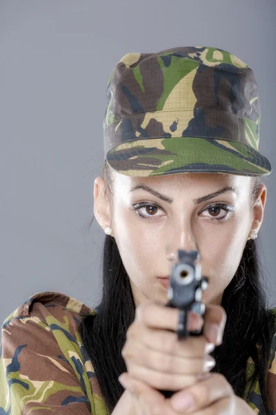 Soldado femenino en uniforme de camuflaje con arma aislada sobre fondo gris — Foto de Stock