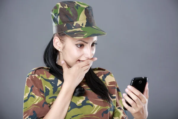 Gelukkige vrouw soldaat kijkt naar een mobiele telefoon — Stockfoto