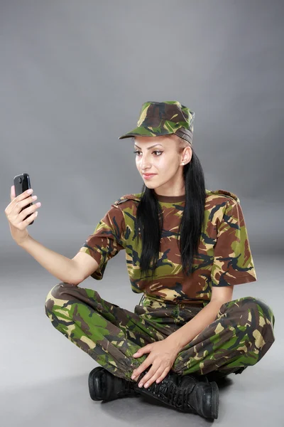 Soldado mulher feliz olha para um telefone celular — Fotografia de Stock