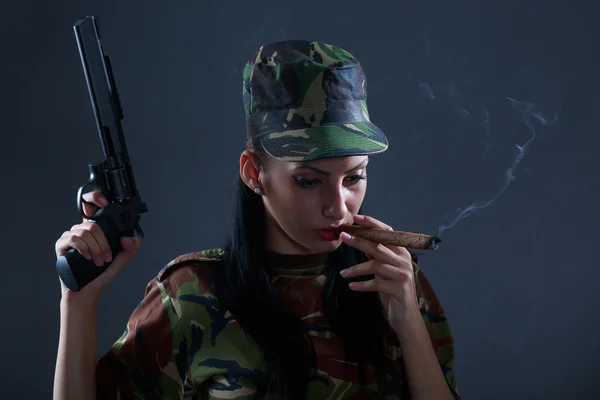 Female soldier in camouflage uniform with gun and cigar smoke — Stock Photo, Image