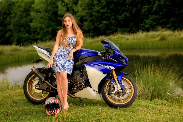 Mooie jonge vrouw met een snelheid van de motorfiets in de natuur — Stockfoto