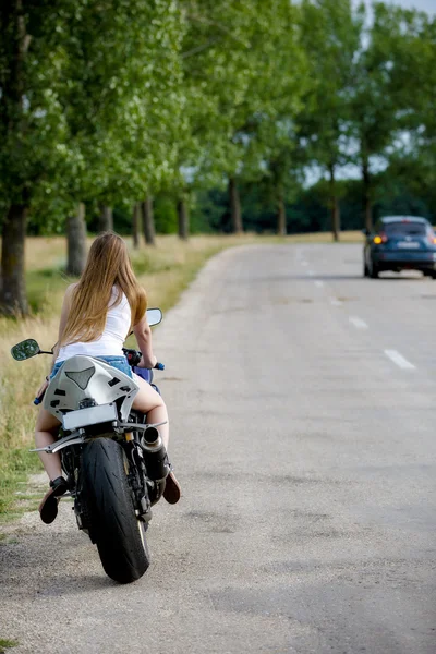 Bela jovem com uma velocidade de motocicleta na natureza — Fotografia de Stock