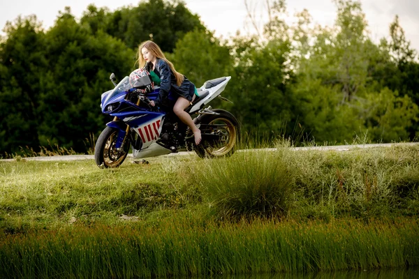 Hermosa mujer joven con una velocidad de motocicleta en la naturaleza — Foto de Stock