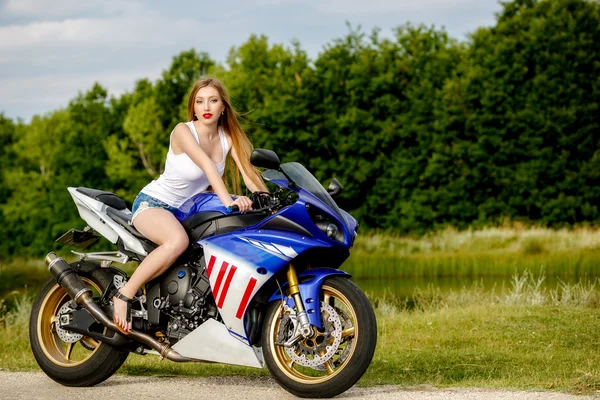 Όμορφη νεαρή γυναίκα με μια ταχύτητα μοτοσικλέτας στη φύση — Φωτογραφία Αρχείου
