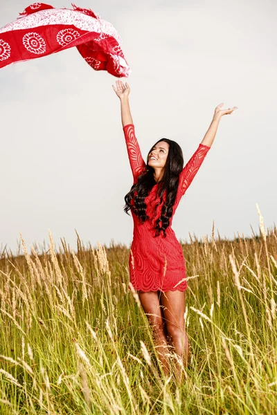 Belle femme brune avec une écharpe dans un champ au coucher du soleil — Photo