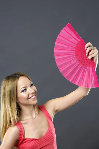 Hermosa mujer en vestido rosa con abanico rojo — Foto de Stock