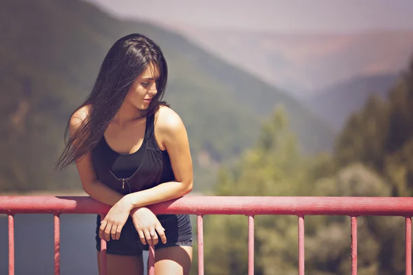 A beautiful young woman posing on a bridge — Stock Photo, Image